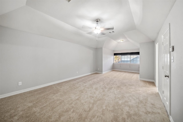 interior space featuring ceiling fan, vaulted ceiling, baseboards, and light carpet