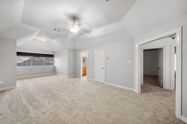 unfurnished bedroom featuring visible vents, connected bathroom, baseboards, vaulted ceiling, and light carpet