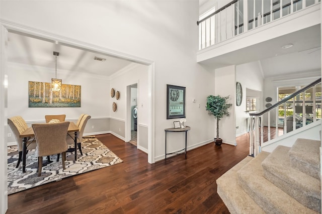 dining area with visible vents, baseboards, stairs, a high ceiling, and wood finished floors