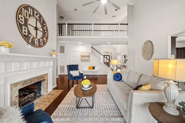 living area with visible vents, a tile fireplace, stairs, and wood finished floors