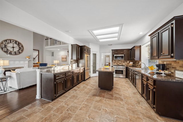 kitchen with tasteful backsplash, dark brown cabinetry, stone counters, appliances with stainless steel finishes, and a sink