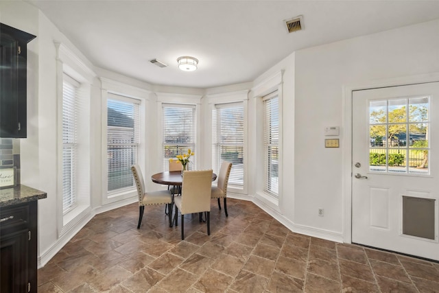 dining space featuring baseboards, visible vents, and stone finish flooring