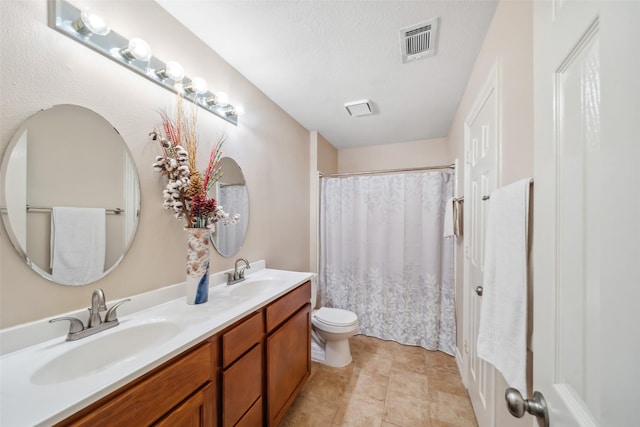 bathroom featuring double vanity, visible vents, toilet, and a sink