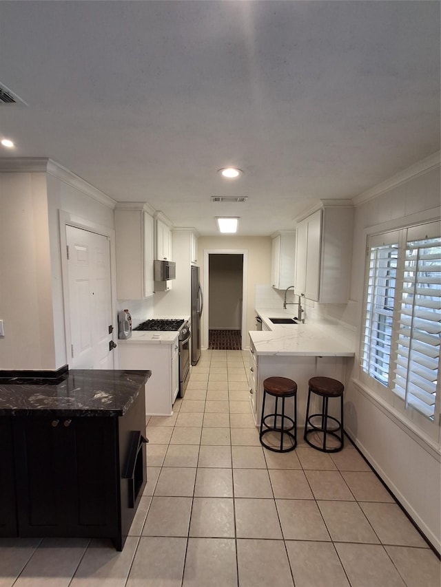 kitchen featuring visible vents, ornamental molding, a sink, appliances with stainless steel finishes, and light tile patterned floors