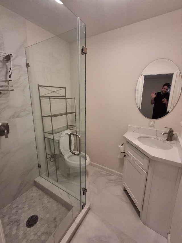 bathroom with vanity, baseboards, a stall shower, toilet, and marble finish floor