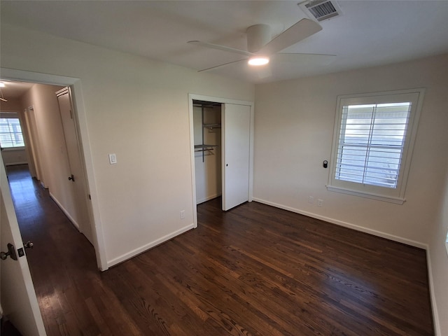 unfurnished bedroom featuring visible vents, ceiling fan, baseboards, a closet, and dark wood-style flooring