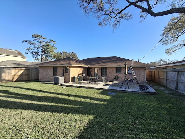 rear view of property featuring a lawn, a fenced backyard, a wooden deck, brick siding, and central AC unit