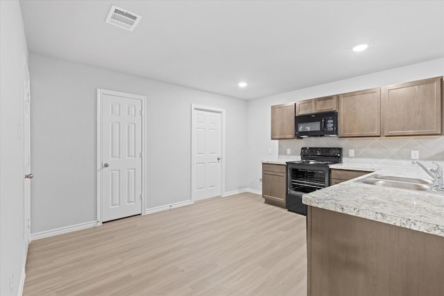 kitchen with visible vents, light wood-type flooring, black appliances, a sink, and light countertops