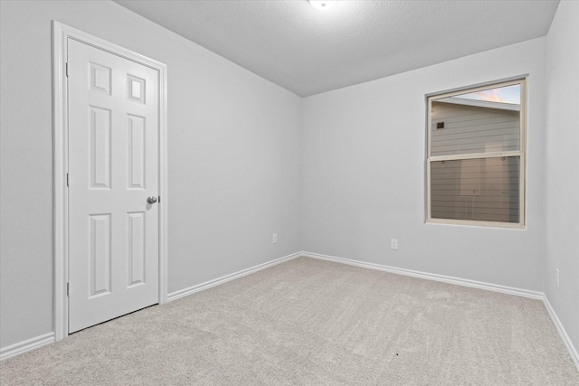 spare room with carpet flooring, baseboards, and a textured ceiling