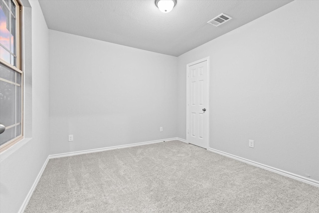 unfurnished room featuring visible vents, a textured ceiling, baseboards, and carpet floors