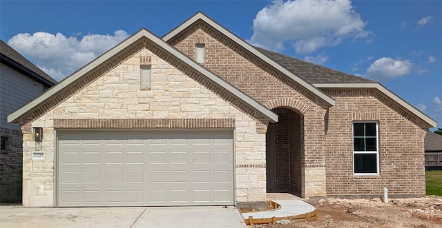 6325 Fulton Dr, College Station, TX 77845 - french country inspired facade with brick siding, driveway, an attached garage, and stone siding
