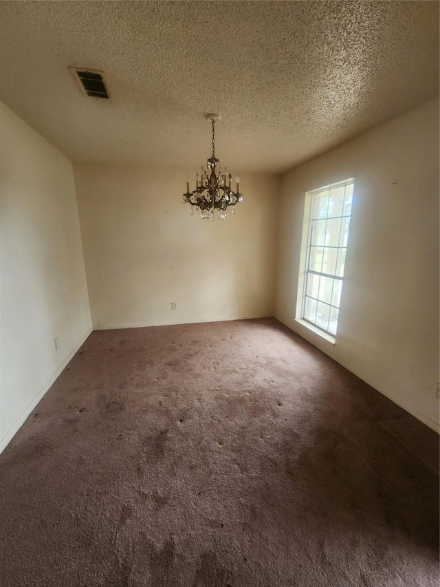 unfurnished dining area featuring visible vents, a textured ceiling, a chandelier, and carpet flooring