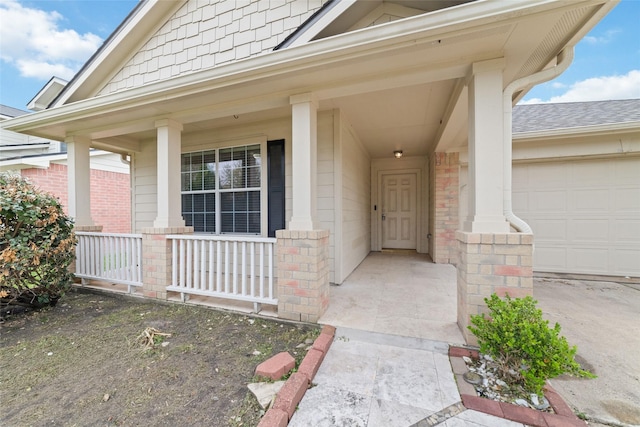 doorway to property featuring a garage, brick siding, and covered porch