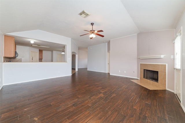 unfurnished living room featuring visible vents, dark wood finished floors, vaulted ceiling, and a tile fireplace