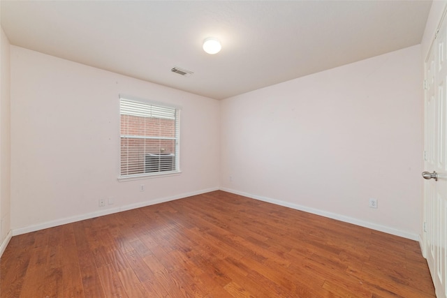 unfurnished room featuring baseboards, visible vents, and wood-type flooring