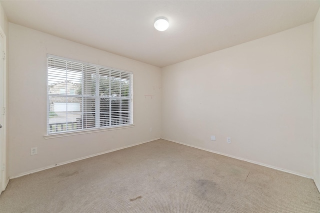 carpeted spare room featuring baseboards