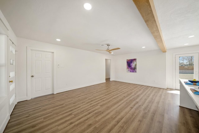 unfurnished living room featuring beamed ceiling, baseboards, and wood finished floors