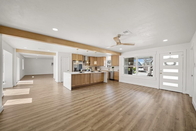 kitchen with visible vents, light wood-style flooring, a center island, stainless steel appliances, and light countertops