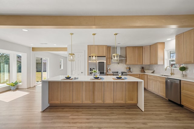 kitchen featuring light wood-type flooring, a sink, appliances with stainless steel finishes, wall chimney exhaust hood, and light countertops