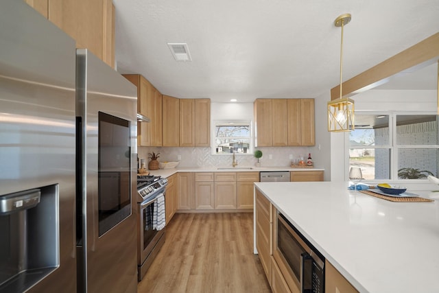 kitchen with tasteful backsplash, visible vents, light brown cabinets, stainless steel appliances, and a sink