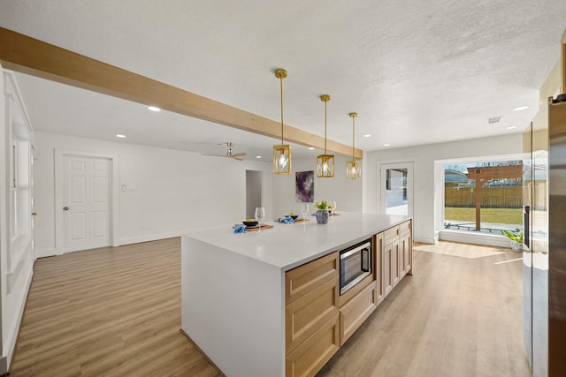 kitchen with light countertops, light wood-style floors, appliances with stainless steel finishes, open floor plan, and a center island