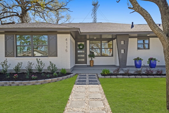 view of front of property featuring a front yard, a porch, brick siding, and a shingled roof