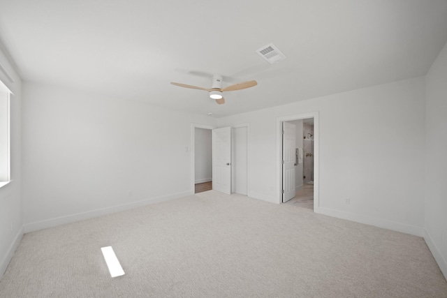 unfurnished bedroom with baseboards, visible vents, ceiling fan, light carpet, and connected bathroom