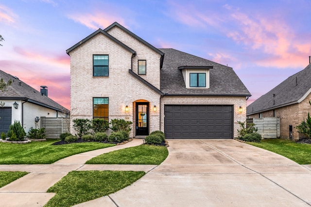 french country style house featuring brick siding, a shingled roof, concrete driveway, and fence