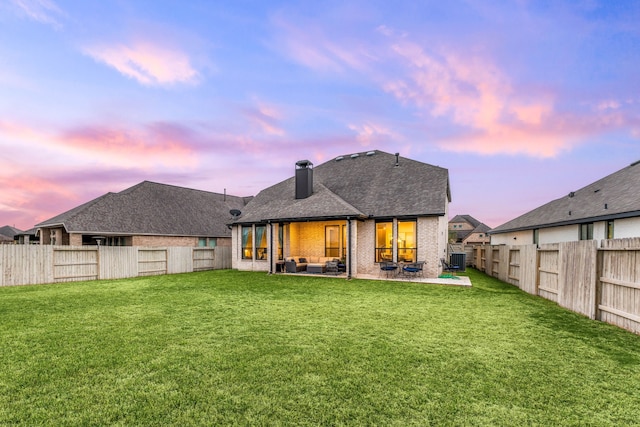 back of house featuring an outdoor living space, a yard, a fenced backyard, and a patio area