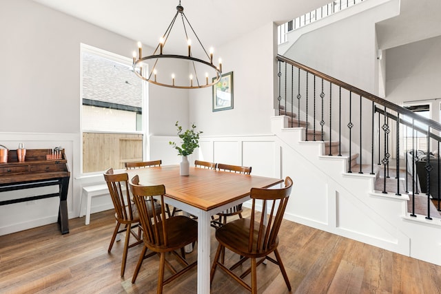 dining space featuring stairway, wood finished floors, and a decorative wall