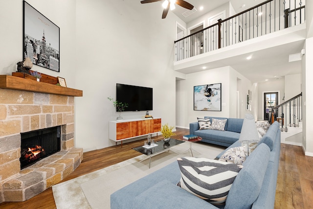 living room with a ceiling fan, wood finished floors, stairway, a fireplace, and baseboards