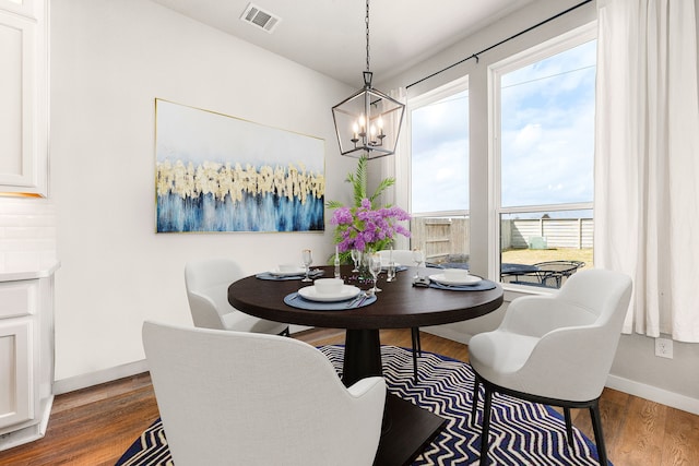 dining space with dark wood-style floors, visible vents, baseboards, and a notable chandelier