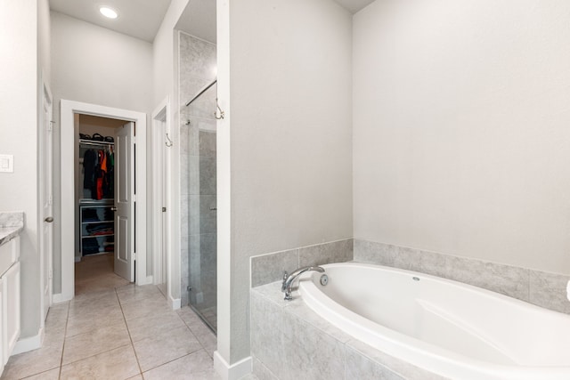 bathroom with tile patterned floors, a walk in closet, a garden tub, a shower stall, and vanity