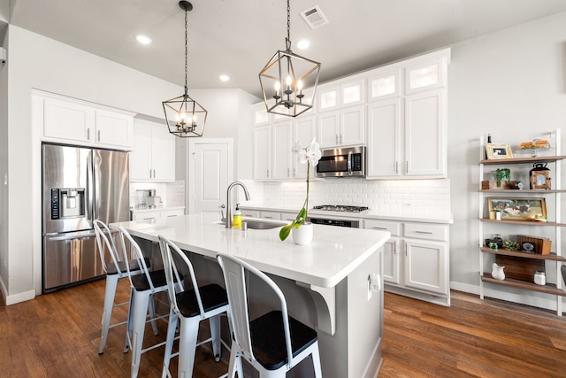 kitchen with visible vents, a sink, appliances with stainless steel finishes, a kitchen breakfast bar, and a kitchen island with sink