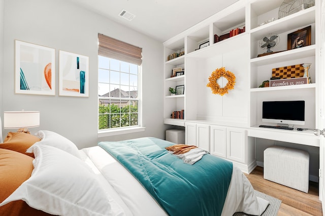 bedroom featuring built in study area, visible vents, and light wood-type flooring