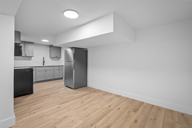 kitchen with a sink, baseboards, tasteful backsplash, and freestanding refrigerator