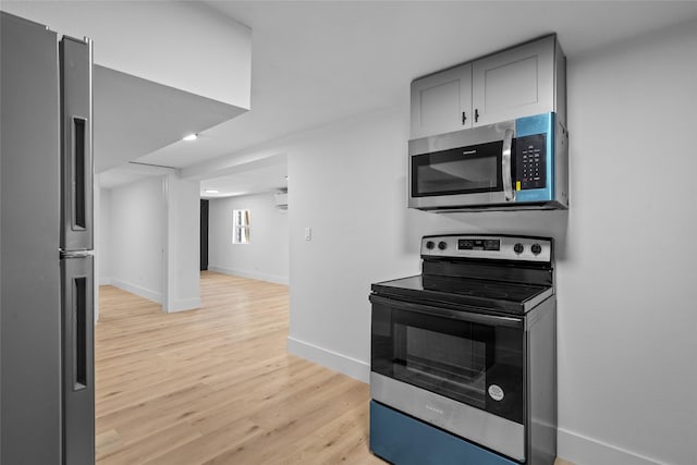 kitchen featuring baseboards, gray cabinets, an AC wall unit, appliances with stainless steel finishes, and light wood-type flooring