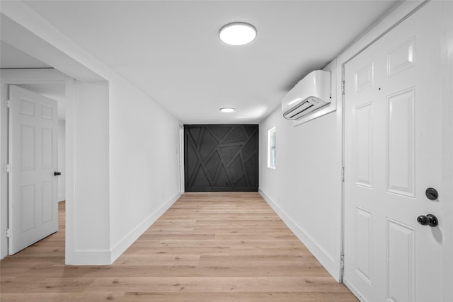 hall with light wood-type flooring, baseboards, and a wall unit AC