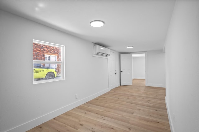 hallway with baseboards, light wood-type flooring, and a wall mounted air conditioner