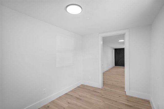 spare room featuring baseboards and light wood finished floors