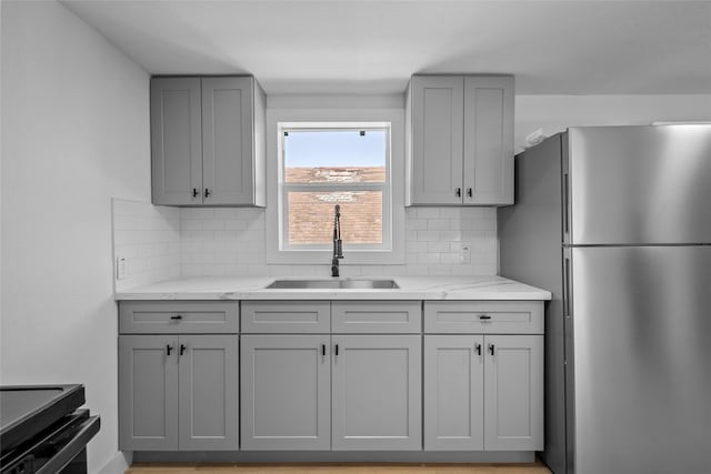 kitchen with a sink, gray cabinets, and freestanding refrigerator