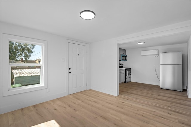 foyer entrance with baseboards, light wood-style floors, and a wall mounted AC