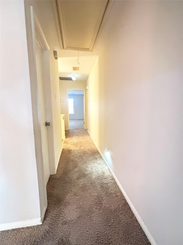 hallway with attic access, carpet, and baseboards