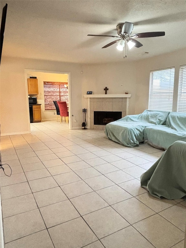 bedroom with a textured ceiling, light tile patterned floors, a ceiling fan, and a tile fireplace