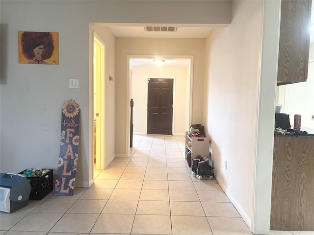 hall with light tile patterned floors, visible vents, and baseboards