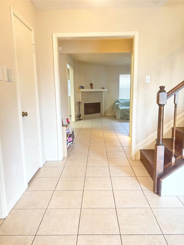 hallway with light tile patterned floors, stairs, and baseboards