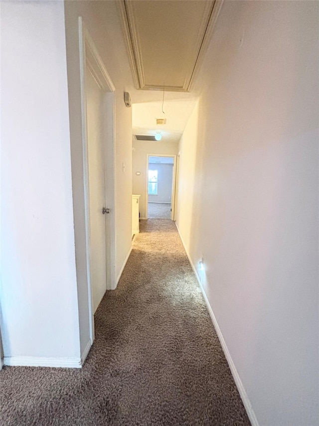 hallway with baseboards, carpet floors, and attic access