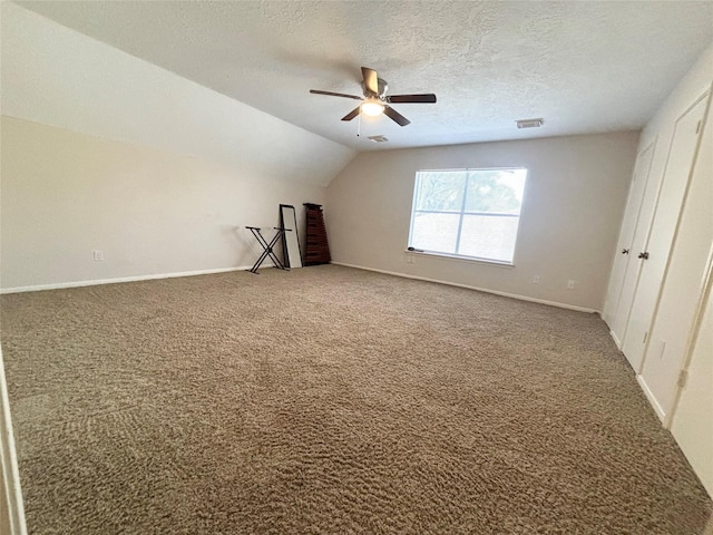 interior space featuring baseboards, visible vents, vaulted ceiling, a textured ceiling, and carpet flooring