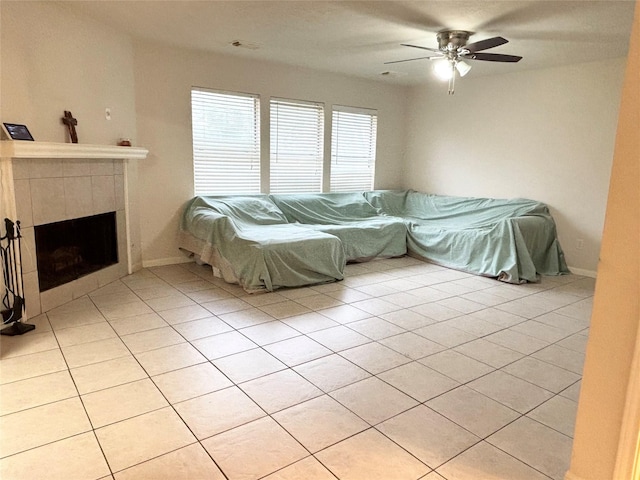 living room with light tile patterned floors, a tile fireplace, baseboards, and ceiling fan