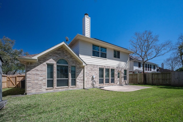 rear view of property featuring a patio, brick siding, a lawn, and a fenced backyard